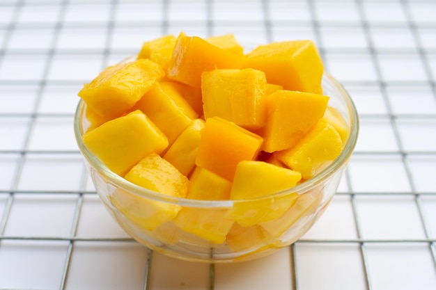 Tropical fruit, Mango cube slices in glass bowl on white background.