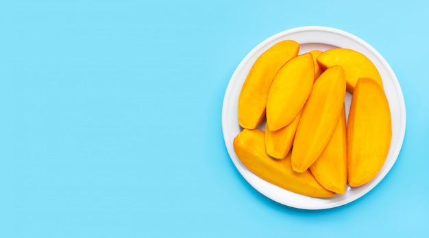 Tropical fruit, Mango slices on white dish on blue background.