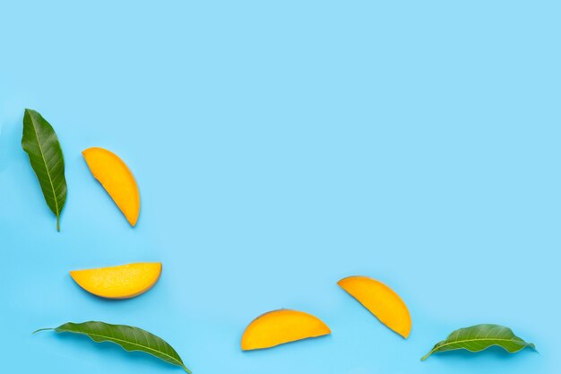 Tropical fruit, Mango slices with leaves on blue background.