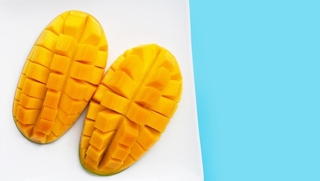 Tropical fruit Mango in white plate on blue background Top view
