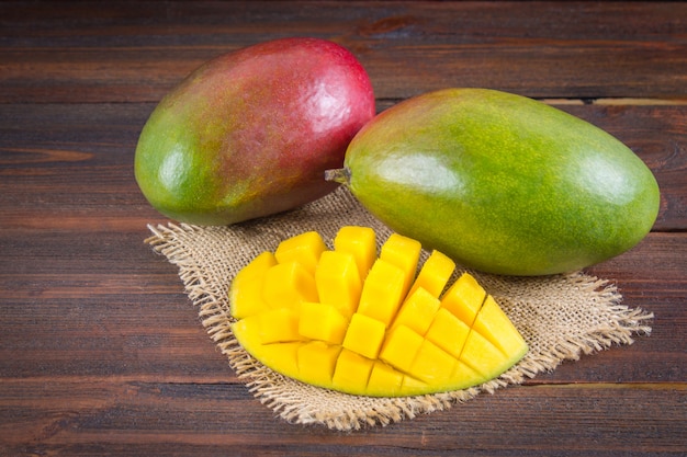 Tropical fruit mango on a wooden background, whole or sliced.