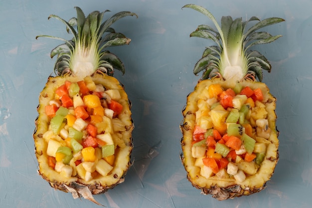 Tropical fruit salad in pineapple halves on a light blue background, Closeup, Top view