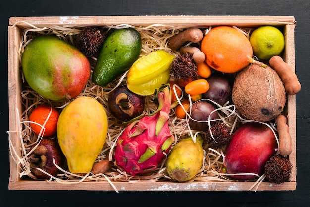 Tropical fruit in a wooden box Papaya Dragon Fruit rambutan tamarind cactus fruit avocado granadilla carambola kumquat mango mangosteen passionfruit coconut