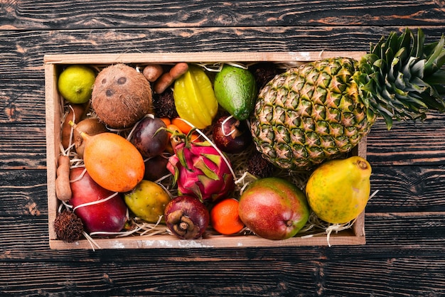 Tropical fruit in a wooden box Papaya Dragon Fruit rambutan tamarind cactus fruit avocado granadilla carambola kumquat mango mangosteen passionfruit coconut