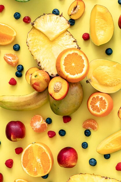Tropical fruits and berries on a yellow background flat lay