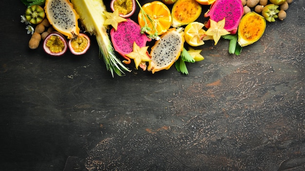 Tropical fruits passion fruit pineapple dragon fruit kiwi and cactus on a brown background Top view