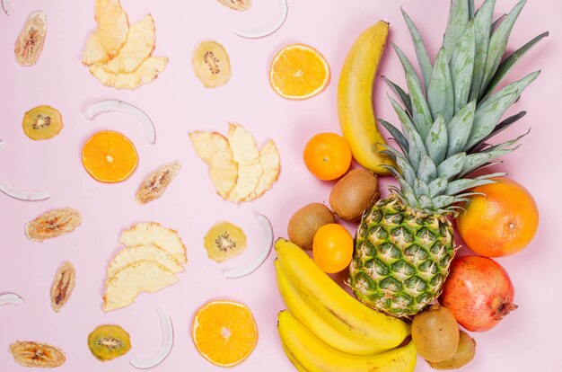 Tropical fruits. Pineapple. coconut, orange, bananas and dry fruit chps on pink background. Food concept. Summer tropical composition. Top view, copy space.