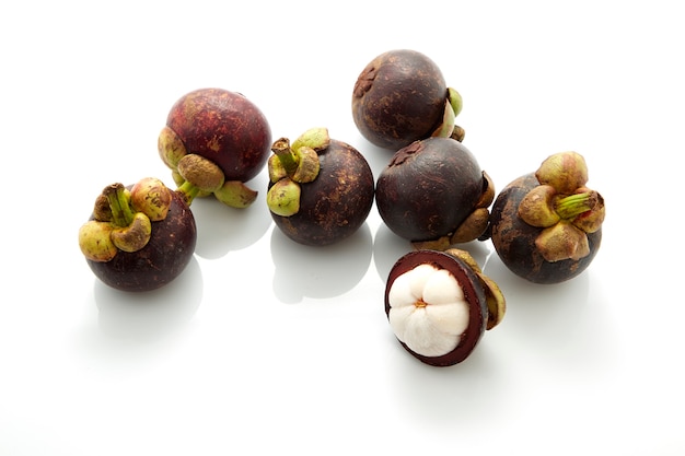 Tropical fruits whole mangosteen and another cut in half on white background