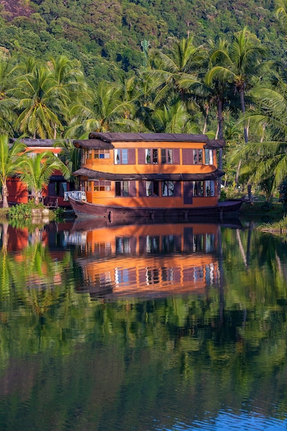 Тропический дом в виде корабля в большой лагуне рядом с морем в джунглях с зелеными пальмами. Роскошный пляжный курорт на острове в Таиланде. Концепция природы и путешествий