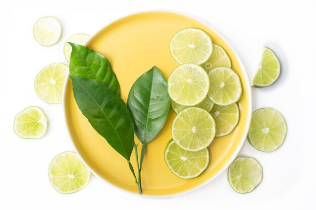 Tropical and refreshing concept with lemon leaves and slices on yellow plate