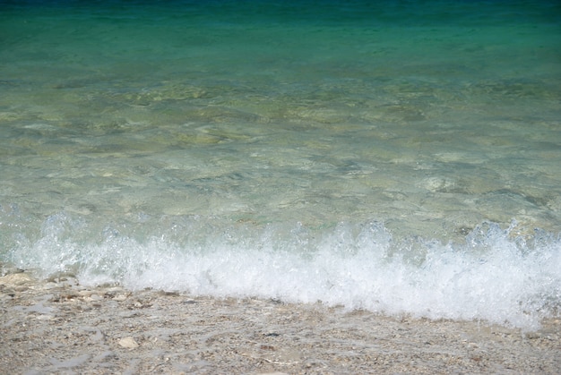 Tropical sand beach with sea waves and stones.