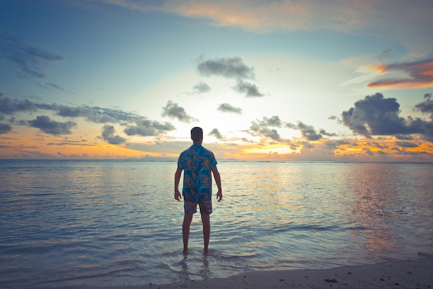 美しい島の海の前で熱帯の夕日。瞬間を楽しんでいる休暇中の男