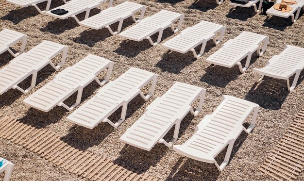 Tropical vacation background White deck chairs for outdoor activities on the beach View from above Bright sunlight