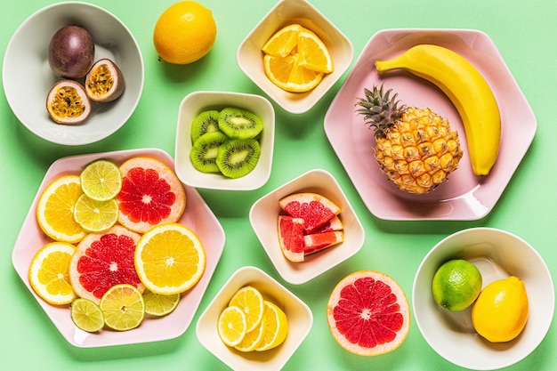 Tropisch fruit geheel en plakjes op platen, bovenaanzicht.