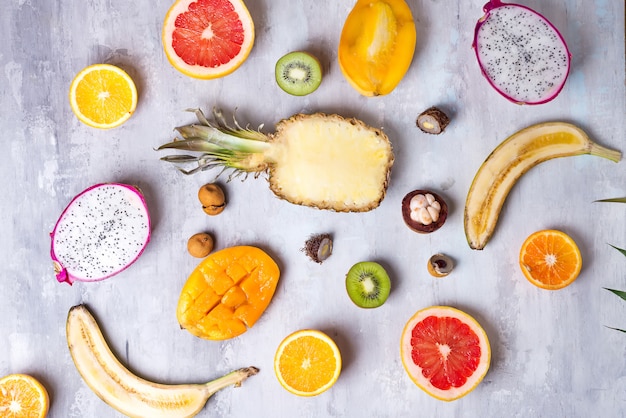 Tropisch fruitassortiment op een steen licht patroon als achtergrond. Bovenaanzicht. Ruimte kopiëren