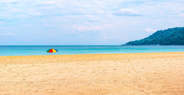 Tropisch leeg zandstrand op een eiland in Thailand met een heldere kleurrijke parasol in het zand Reizen en toerisme Panorama met plaats voor tekst