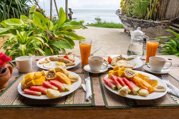 Tropisch ontbijt met fruit, koffie en roerei en bananen pannenkoek