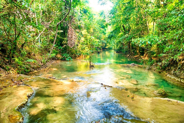 Tropisch regenwoudlandschap met stromende beek en zonnestralen Erawan National park Kanchanaburi ThailandxA