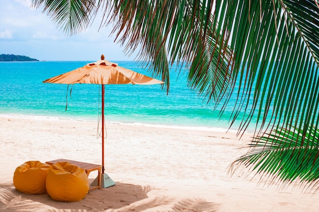 Tropisch strand met palmbomen met een parasol en poefs om te relaxen