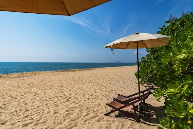 Tropisch strand met parasol onder de palmen in zonlicht, vakantie