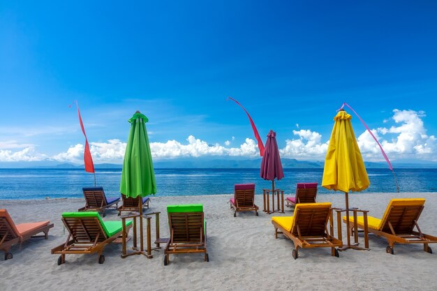 Tropisch zandstrand en blauwe hemel met wolken. Lege ligbedden en gesloten parasols