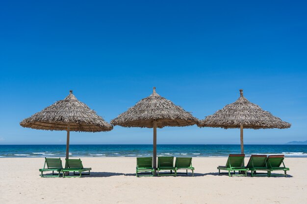 Tropisch zandstrand en zomerzeewater met blauwe lucht en drie stroparaplu's in de stad Danang, Vietnam. Reis- en natuurconcept