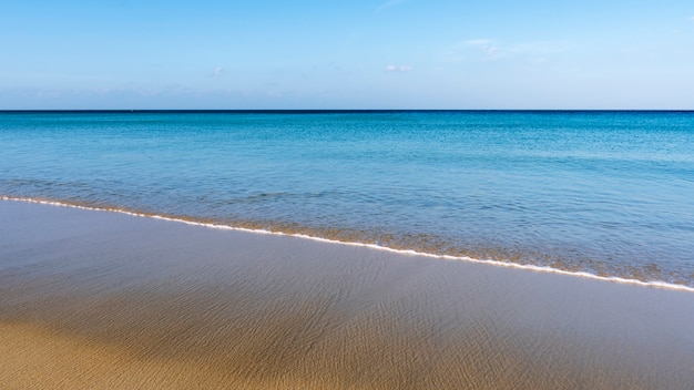 Tropisch zandstrand met blauwe lucht en golven op zandige kust