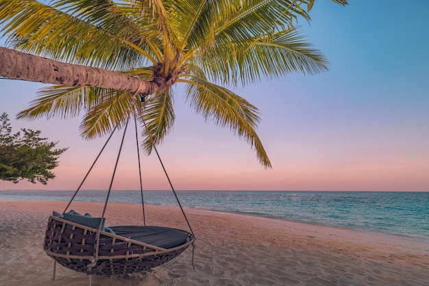 Tropisch zonsondergangstrandpanorama als zomerlandschap met ontspannen strandschommel of hangmat op kokospalm