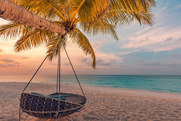 Tropisch zonsondergangstrandpanorama als zomerlandschap met ontspannen strandschommel of hangmat op kokospalm