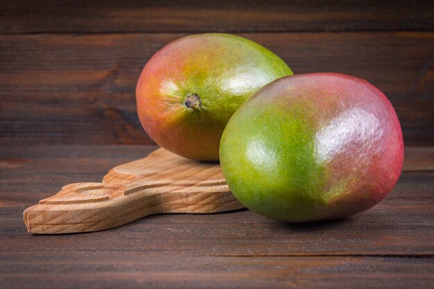 Foto tropische fruitmango op een houten achtergrond, geheel of gesneden.