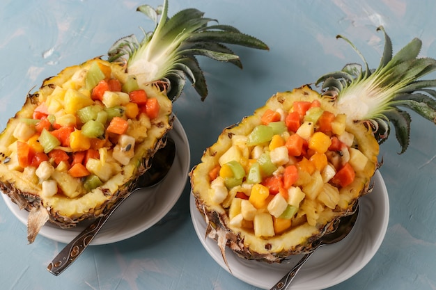 Tropische fruitsalade in ananas helften op een licht blauwe ondergrond, bovenaanzicht