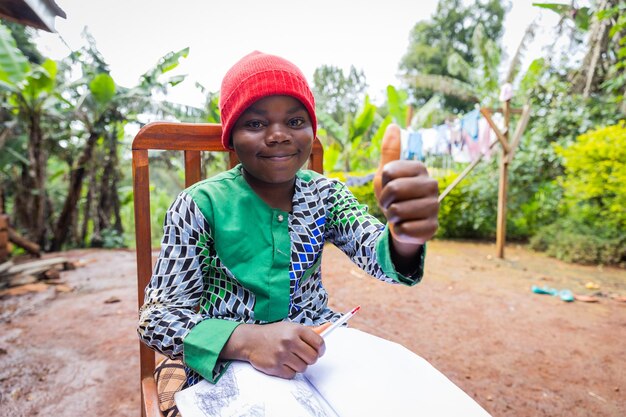 Foto trotste afrikaanse schooljongen met duimen omhoog voltooit zijn schoolopdracht