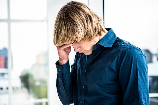 Troubled hipster businessman holding his head in his office