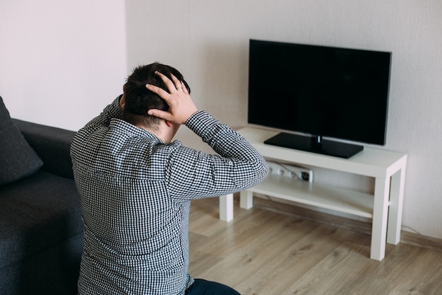 Troubled man watching tv news