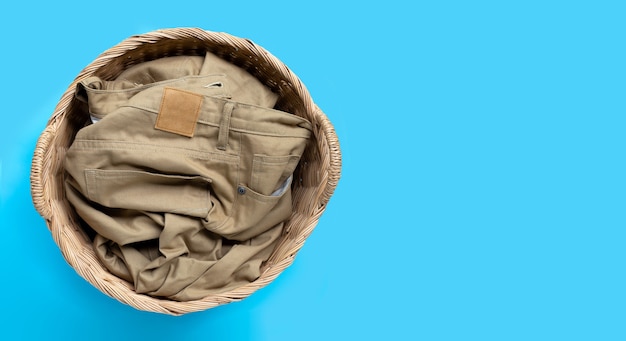 Trousers in laundry basket on blue background. Copy space