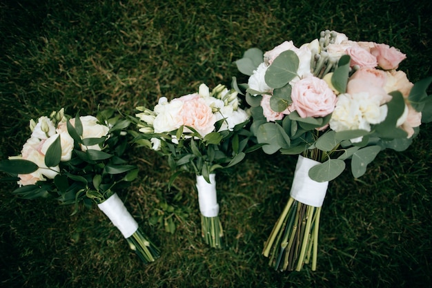 Trouwboeketten van witte en roze rozen liggen op het groene gras