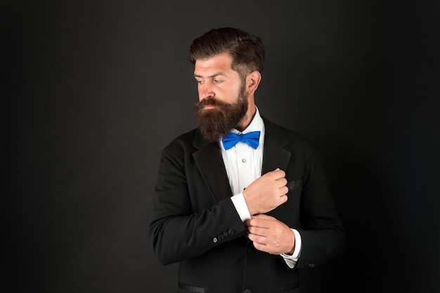 Trouwdag concept Stijlvolle bruidegom Elegante collectie Netjes en opgeruimd Stylist mode-expert Pak stijl Modetrends voor bruidegom Bruidegom bebaarde hipster man draagt smoking en blauwe vlinderdas