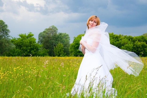 Trouwdag schoonheid natuur concept in het midden van het veld is er een geweldige vrouw die witte bruidsjurk draagt, ze draait om zichzelf heen en pailletten schijnen in het licht van de zon