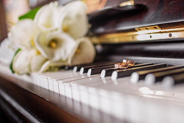 Trouwringen en een boeket witte calla's op de pianotoetsen.