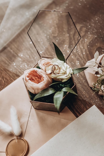 Foto trouwringen liggen op een mooie doos met bloemen als bruidsaccessoires