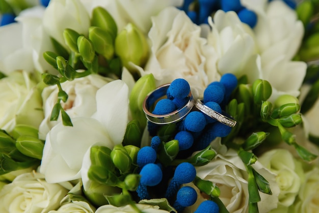 Trouwringen voor bruid en bruidegom op boeket van verse blauwe bloemen