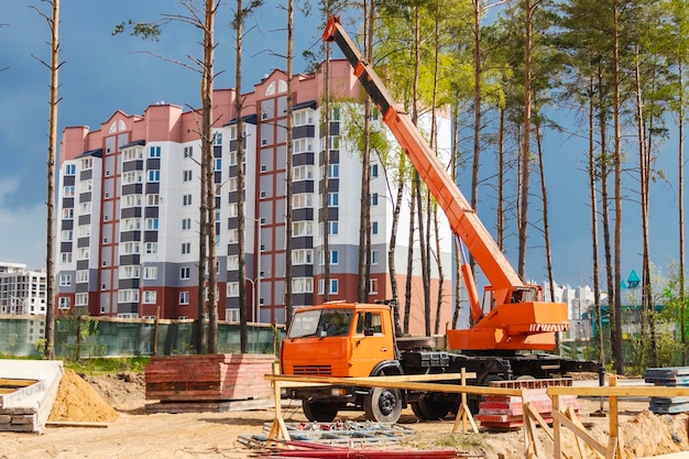 A truck crane at a construction site is ready to lift loads Construction of a new residential area on the outskirts of the city in a forested area