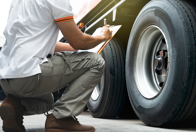 Photo truck driver is inspecting safety of wheels truck.