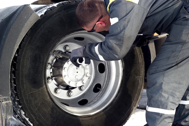 Truck driver using spanner for tyre repair.