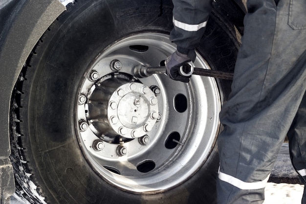 Truck driver using wrench for tyre repair.