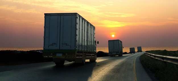 Camion sulla strada della strada principale con il contenitore, industriale logistico con il cielo di alba