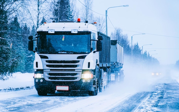 Truck in snow winter road of Finland. Trucker in highway. Lorry doing logistics work. Semi trailer with driver. Big cargo car drive. Freight delivery. Transport export industry. Container with goods