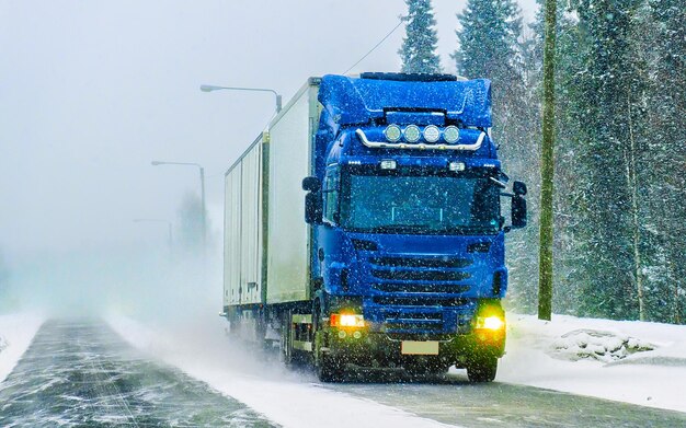 Truck in snow winter road of Finland. Trucker in highway. Lorry doing logistics work. Semi trailer with driver. Big cargo car drive. Freight delivery. Transport export industry. Container with goods