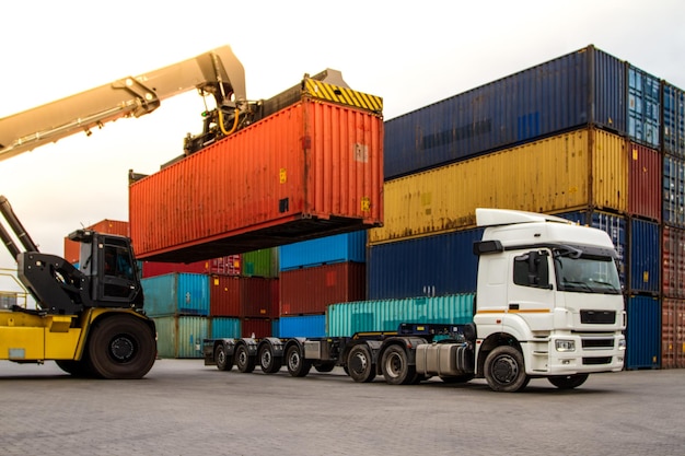Truck while loading in logistic shipping yard with cargo\
container forklift truck handling truck logistic import export\
concept loading and unloading of containers in the port