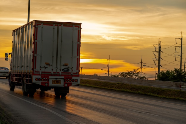 Truck with Cargo driving on road transportation highway at sunset in summer